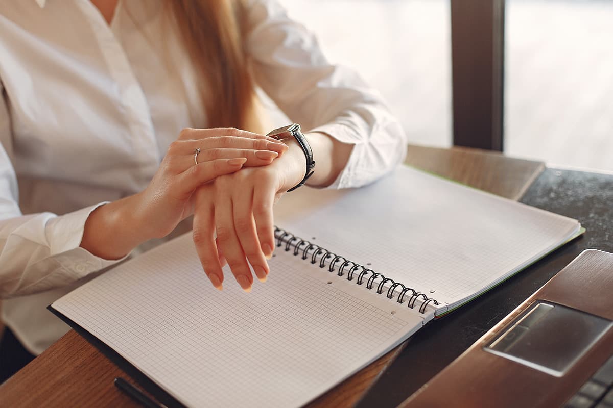 Woman watching her wrist clock by her desk.