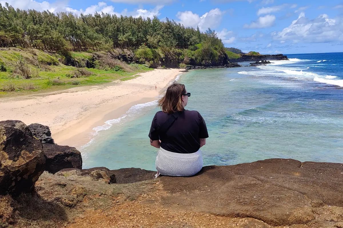 Henkilö istuu selin kameraan Mauritiuksen Gris Gris -rannalla